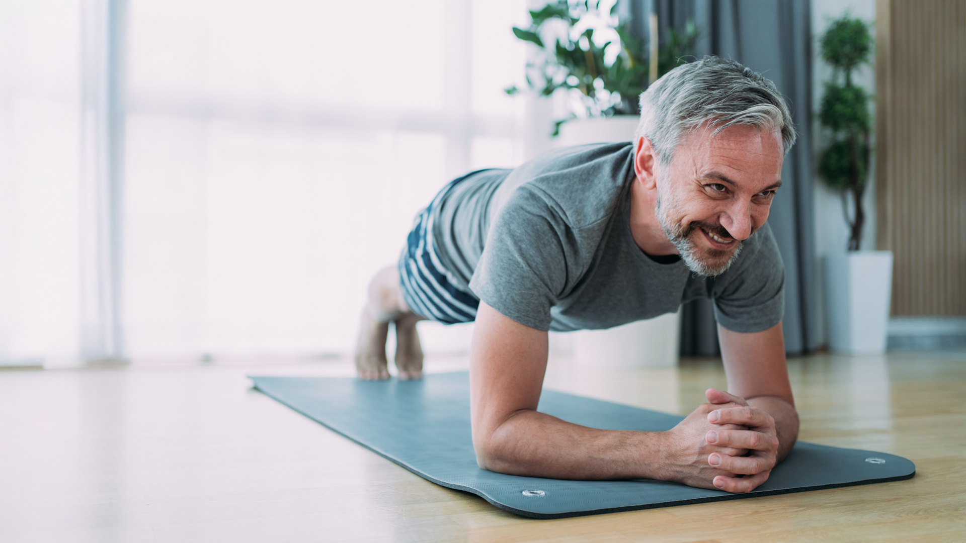 Un homme faisant la planche sur un tapis de yoga pour un ventre plat.